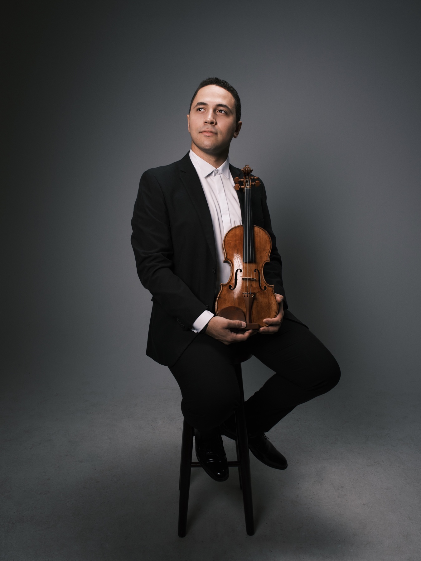 Ocimar Correa Filho seated with a Giuseppe Gagliano violin